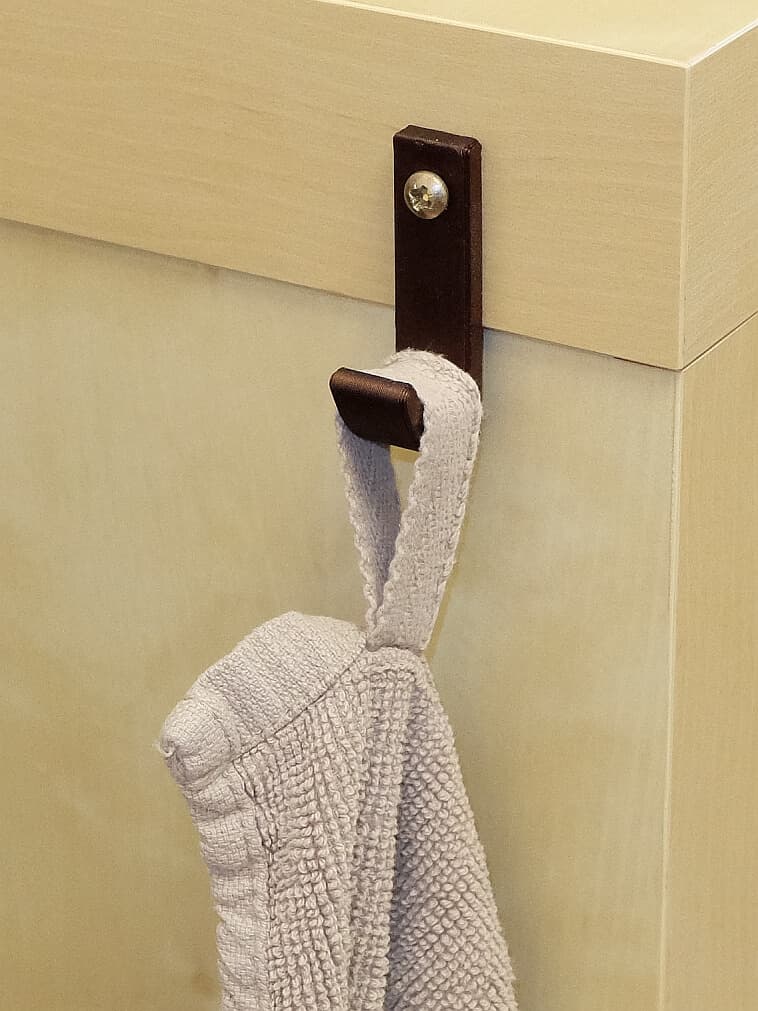Le crochet fixé sur un meuble, avec une serviette suspendue.